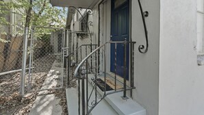 A white building with a blue door, a metal staircase, and a chain-link fence. - Bright 2BR Duplex Mins to Downtown San Antonio (San Antonio)