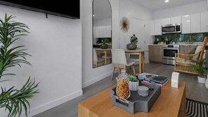 Eine moderne Küche mit weißen Schränken, einer Mikrowelle und einem Backofen. Es gibt eine Essecke mit Tisch und Stühlen sowie einen großen Spiegel an der Wand.