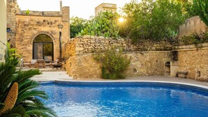 Un espace piscine agrémenté de murs en pierre, d’une arche en pierre et de mobilier d’extérieur.