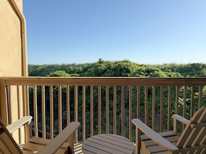 Eine Holzterrasse mit zwei Stühlen und Blick auf einen grasbewachsenen Hügel.