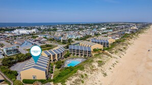 Luchtbeeld van Coastal Carolina Beach, met een hotel aan het strand, meerdere gebouwen, een zwembad en een zandstrand.