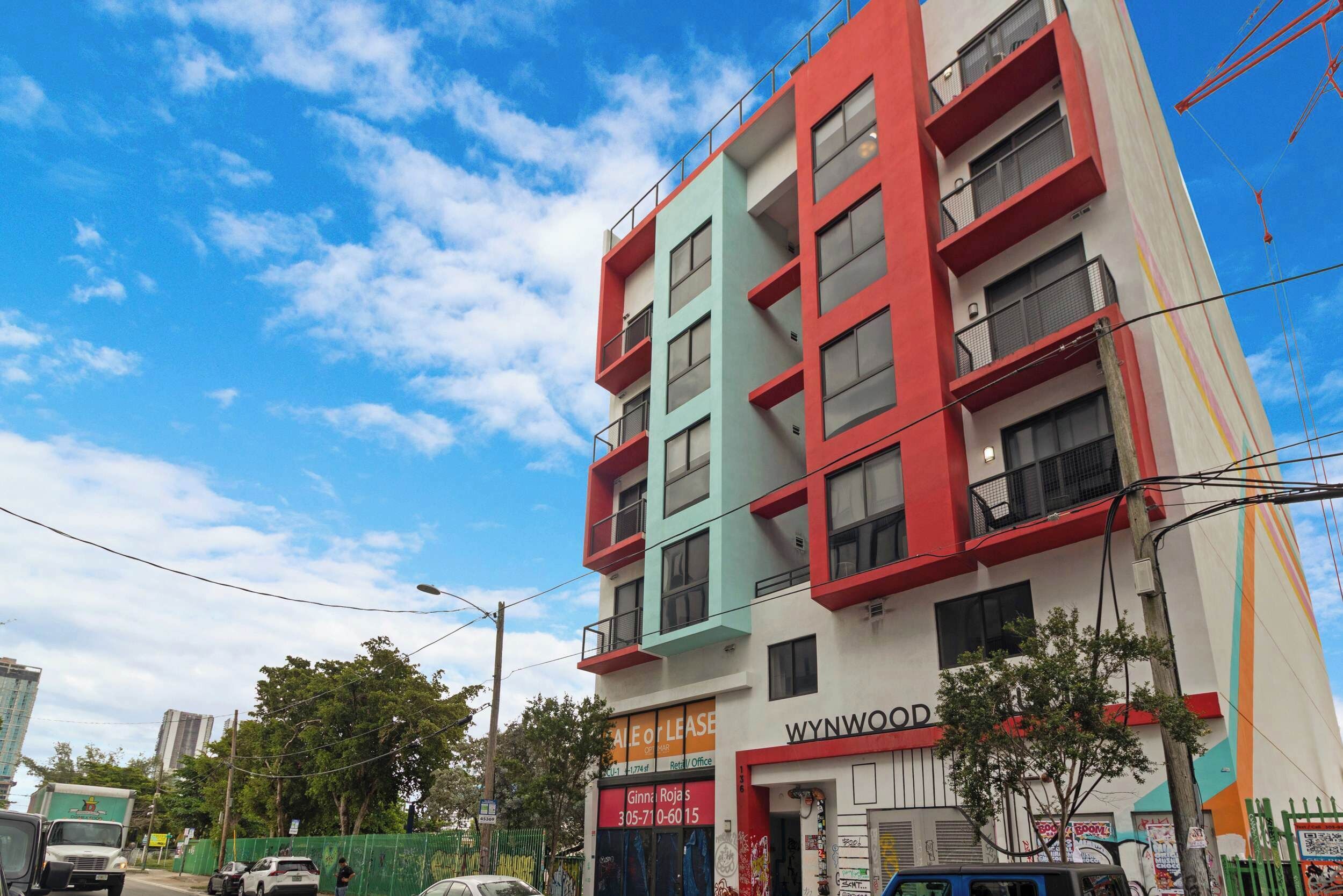 A multi-story building with balconies, a sign for Wynwood, and a visible storefront.