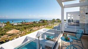 A balcony with a pool, clear blue sky, and a view of the sea and distant buildings.