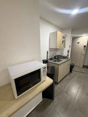 A compact kitchen with a microwave on a wooden shelf, a sink, and a small countertop. - Aparthotel Short Term Rentals Apartments (Armenia)