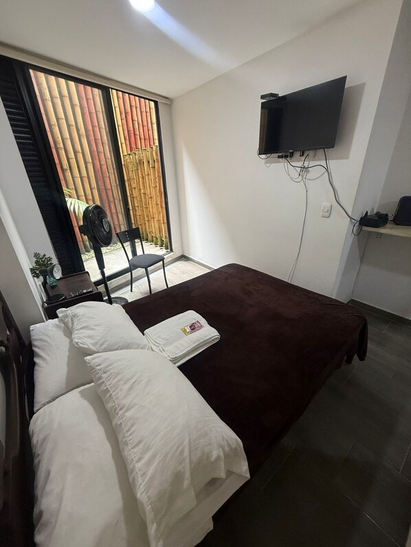 A bedroom with a bed, a TV mounted on the wall, and a sliding glass door leading to an outdoor area. - Aparthotel Short Term Rentals Apartments (Armenia)