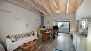 A spacious living area with a wooden ceiling, a dining table with chairs, a sofa, and a kitchen in the background. - Thodoros Apartment – 3 Bedrooms, Sea Views, Family-Friendly (Boikatika Erimitis)