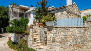 Una casa de piedra con fachada blanca, una valla azul y una escalera que lleva a una puerta.