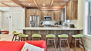 Een moderne keuken met houten kastjes, een roestvrijstalen koelkast en een groot kookeiland met barstoelen.