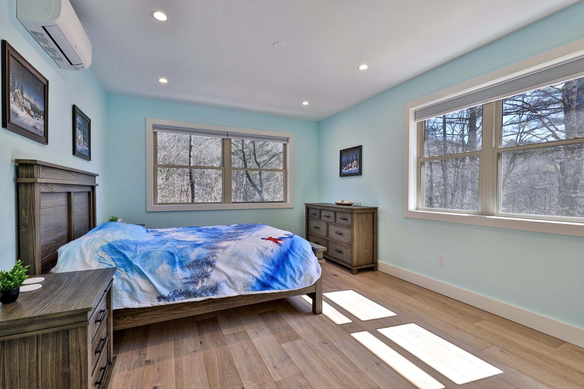 A bedroom with a bed, dresser, window, and wall-mounted air conditioner.