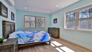 A bedroom with a bed, dresser, window, and wall-mounted air conditioner.