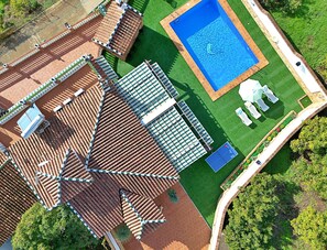 Vista aérea de um hotel com piscina, gramado verde e quadra de tênis.