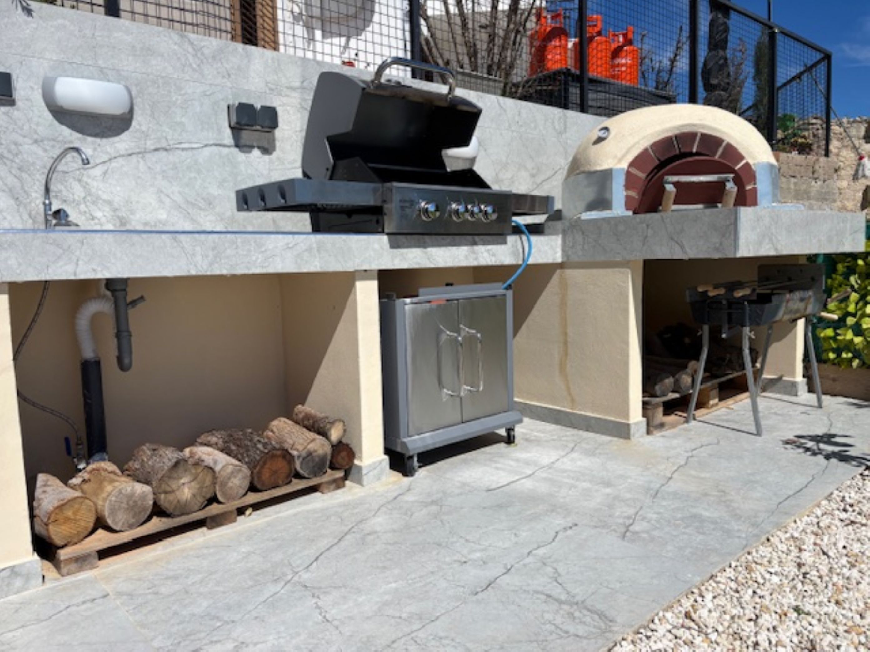 Cucina esterna con barbecue, forno e pensili.