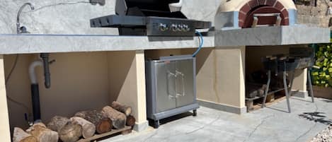 Cucina esterna con barbecue, forno e pensili.