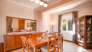 Un coin repas avec une table et des chaises en bois, un grand miroir et un meuble avec des portes en verre.
