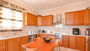 Une cuisine moderne avec des meubles en bois, une hotte de cuisine en acier inoxydable et un dosseret carrelé.
