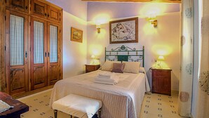 Une chambre à coucher avec un grand lit, une armoire en bois et deux tables de chevet avec des lampes.