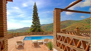 Un espace piscine offrant une vue sur une montagne, un grand arbre et un mur de briques.