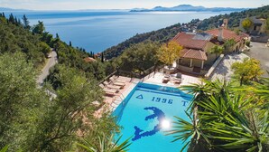 Una piscina con decorazione a forma di delfino, circondata da alberi e vista sul mare.