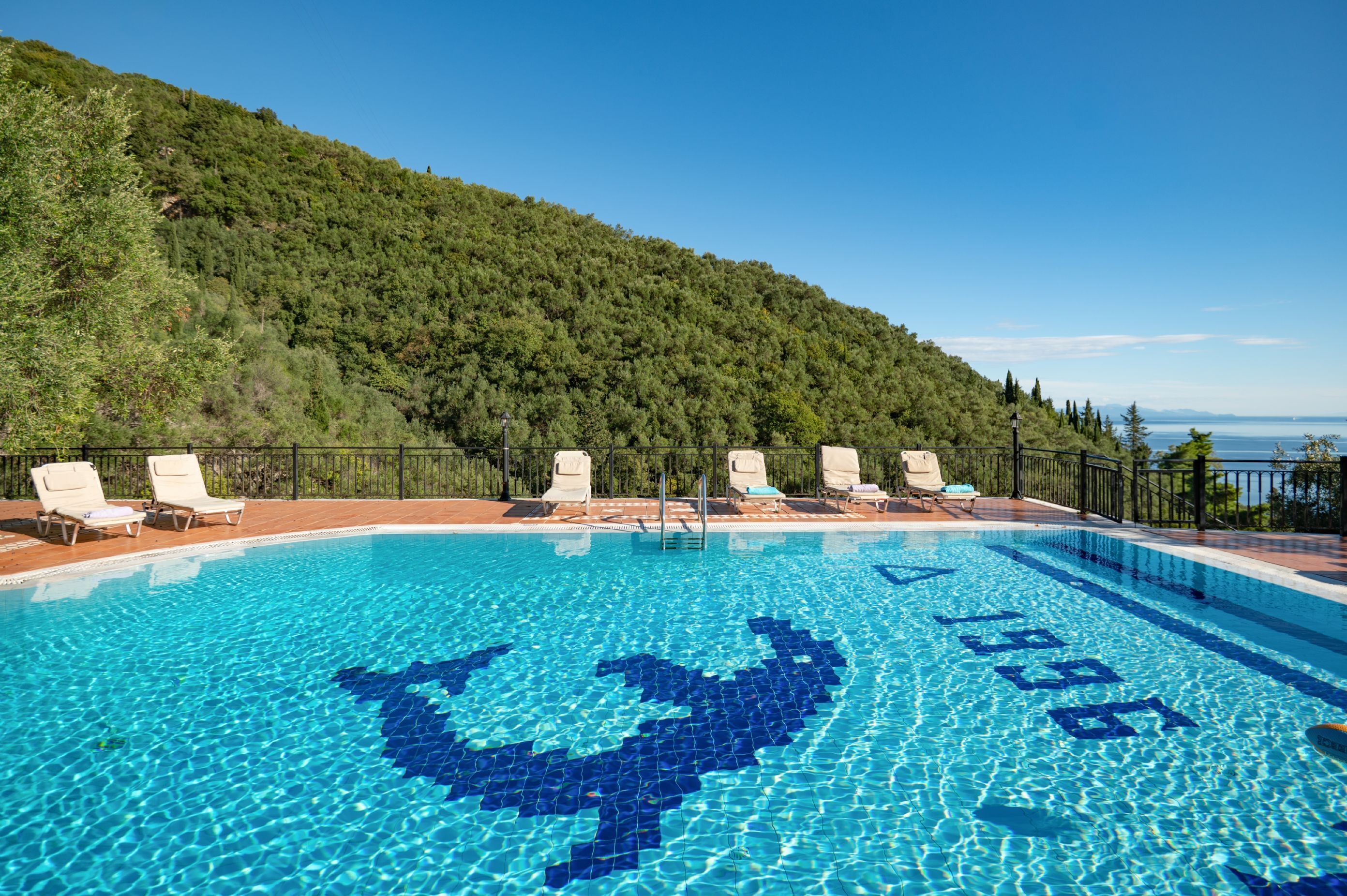 Piscina con sillones de descanso y vista a un paisaje selvático.