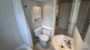 Une salle de bain avec des toilettes, un lavabo et une douche.