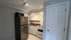 Une cuisine compacte équipée d’un réfrigérateur, d’un four à micro-ondes, d’une cuisinière et de placards.