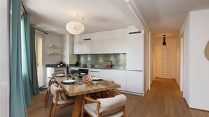 Una cucina moderna con mobili bianchi, un tavolo da pranzo in legno e un lampadario.