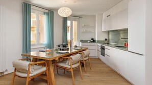 Una cucina moderna con mobili bianchi, un tavolo da pranzo in legno e una lampada a sospensione.