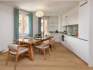 Eine moderne Küche mit weißen Schränken, einem Holztisch und einer Pendelleuchte.