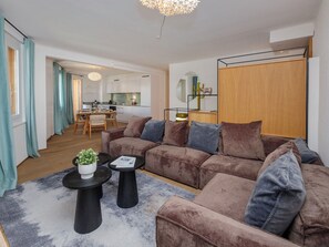Ein modernes Wohnzimmer mit einer Couch, einem Couchtisch und einem Essbereich im Hintergrund.