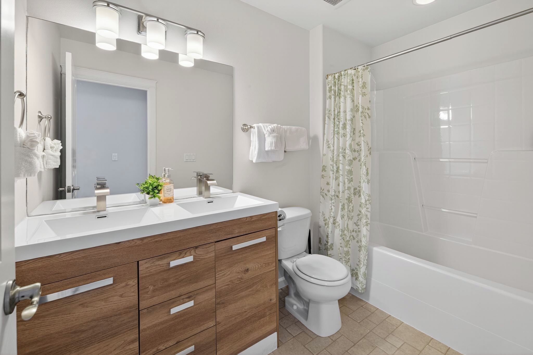 A modern bathroom with a white sink, wooden vanity, a toilet, and a shower area.