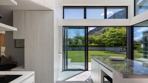 Een moderne keuken met een grote schuifpui die uitkomt op een tuin met uitzicht op bergen.