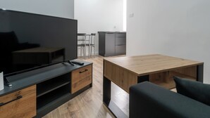 Una sala moderna con televisor de pantalla plana, muebles de madera y un comedor con sillas y una mesa.