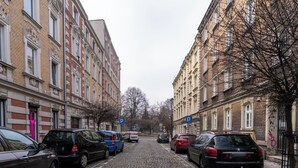 Una calle empedrada bordeada por coches estacionados y edificios históricos.