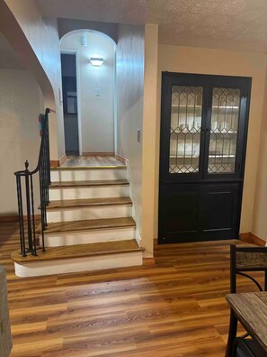A staircase leading to a door with a glass panel, wooden flooring, and a small table with a chair. - Cozy 2-bedroom house in adorable Dayton with AC (Dayton)