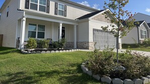 A two-story house with a front porch, a garage, and a well-maintained lawn. - Masters 2026 Rental Home w/Additional Loft in Grovetown, GA! (Grovetown)