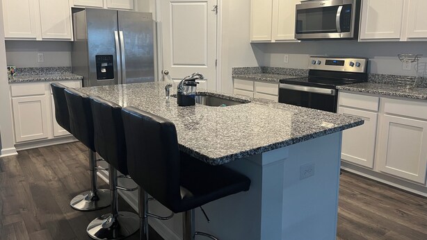 A kitchen with white cabinets, a stainless steel refrigerator, a microwave, and a stove. There is a granite countertop and a sink. - Masters 2026 Rental Home w/Additional Loft in Grovetown, GA! (Grovetown)