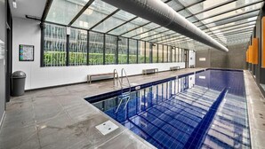 Une piscine intérieure dotée d’un toit en verre, d’un banc et d’une poubelle.