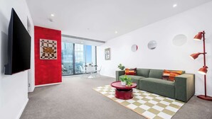 Un salon moderne avec un mur d’accent rouge, un canapé vert, une table basse rouge et un lampadaire.