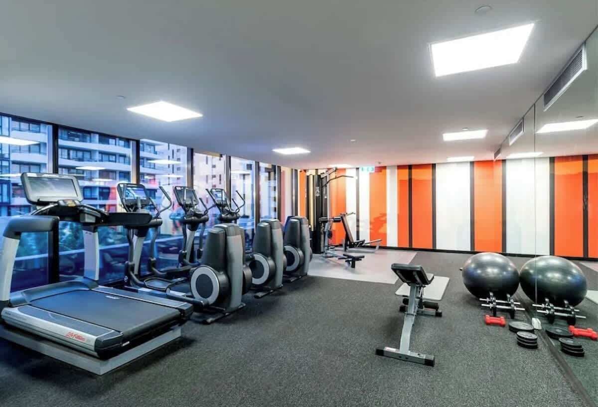 A gym with treadmills, elliptical machines, weight benches, and exercise balls.