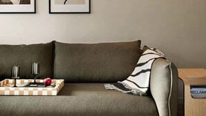 A modern living room with a sofa, two framed artworks, a side table, and a small wooden cabinet. - Scandinavian Suite, Lap Pool, Big Gym, Melbourne (South Yarra)