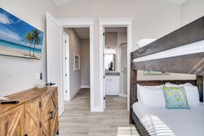 A bedroom with a bunk bed, a wooden dresser, and a painting of a beach scene. - It's Miller Time (Holmes Beach)