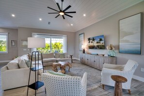 A living room with a sofa, armchairs, a coffee table, and a ceiling fan. - It's Miller Time (Holmes Beach)
