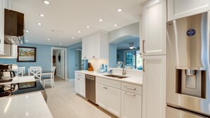 Een moderne keuken met witte kasten, roestvrijstalen apparatuur en inbouwspots.