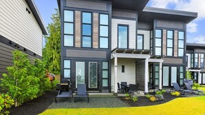 A modern two-story house with a well-maintained lawn and outdoor seating area.