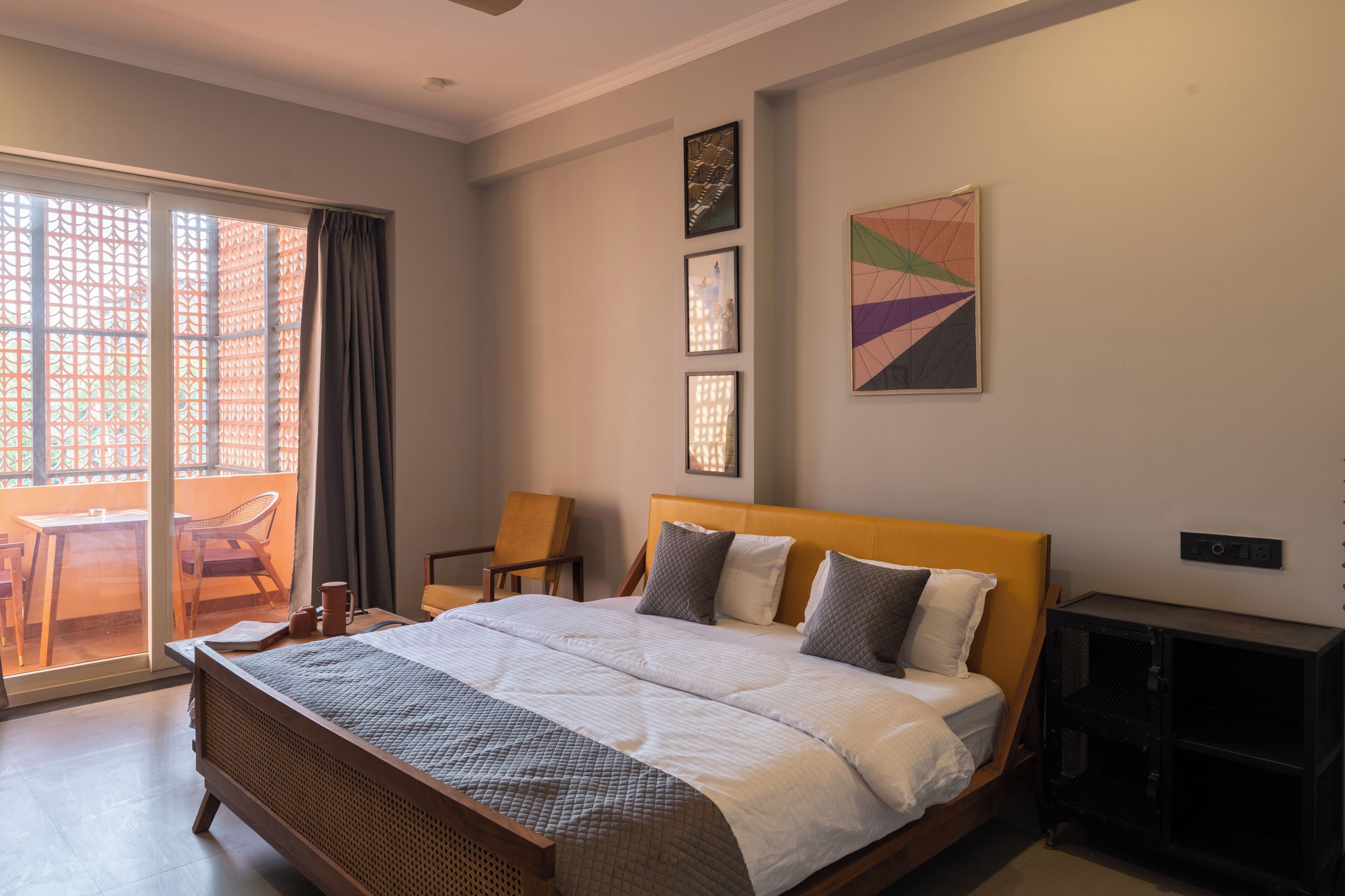 A bedroom with a bed, a chair, a table, and a sliding glass door to an outdoor area.