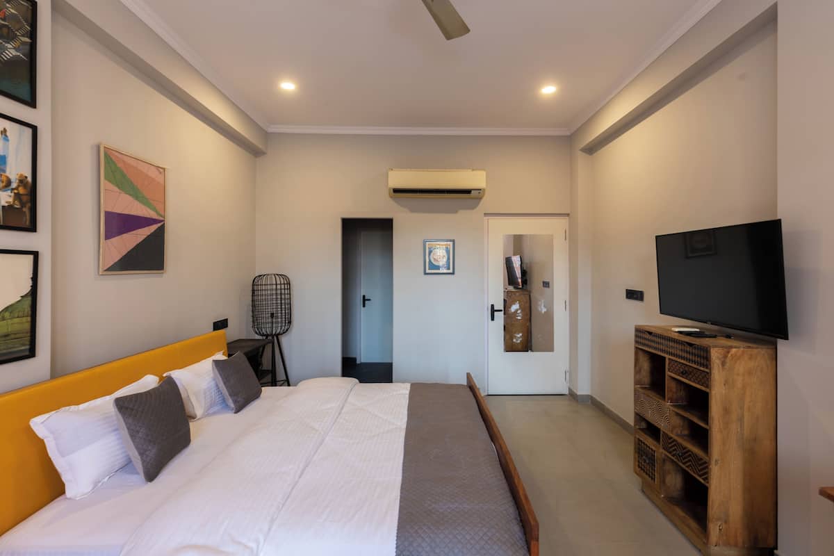 A bedroom with a bed, a television, and an air conditioning unit.