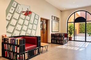 Ett modernt bibliotek med bokhyllor, en röd soffa och ett stort, väggmonterat tangentbord.