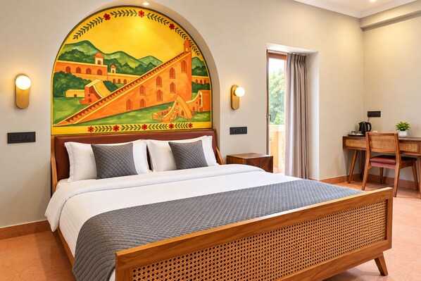 A hotel room with a bed, a desk with a chair, and a large mural on the wall. - Nidra Niwas (Jaipur)