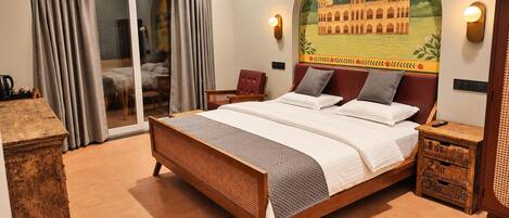 A hotel room with a large bed, a sliding glass door to a balcony, and a mural of a building on the wall.
