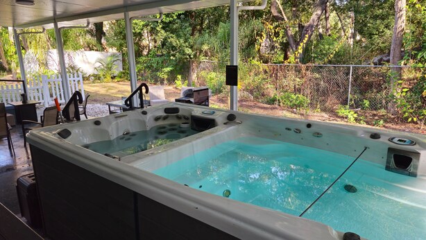 A hot tub with a clear view of the surrounding garden and patio area. - Spacious 5-Bd Tampa Retreat with Dual Jacuzzis. Close to Top Attractions. (Tampa)
